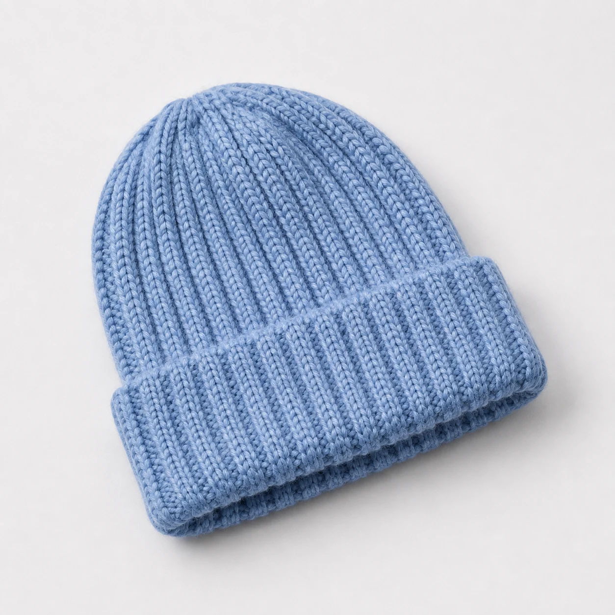Cornflower-blue ribbed beanie on a pale studio background, product concept