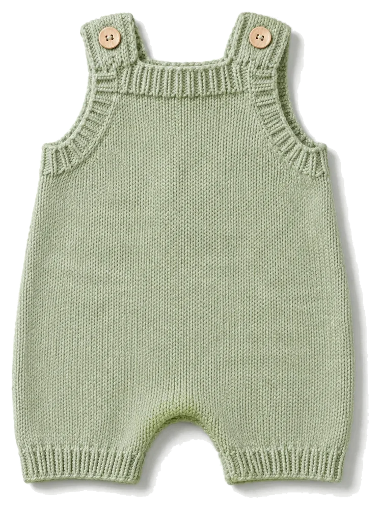 Sage green knitted baby romper on a pale studio background, product concept